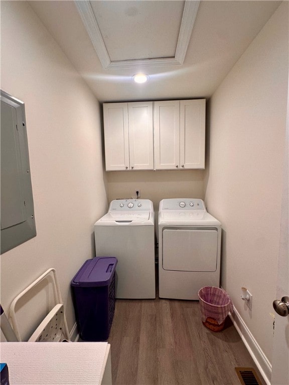 washroom featuring electric panel, washing machine and clothes dryer, cabinets, dark hardwood / wood-style floors, and crown molding