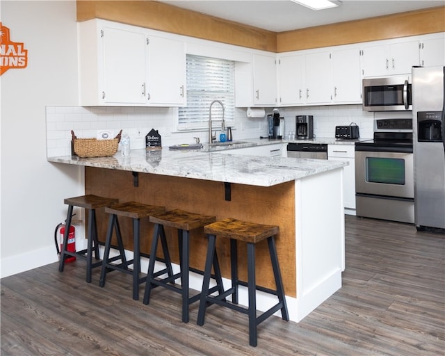 kitchen featuring white cabinets, stainless steel appliances, sink, and kitchen peninsula