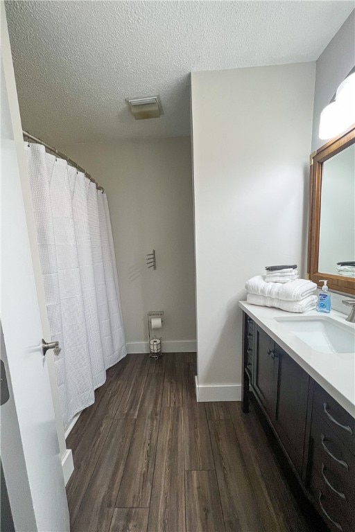 bathroom with wood-type flooring, vanity, walk in shower, and a textured ceiling