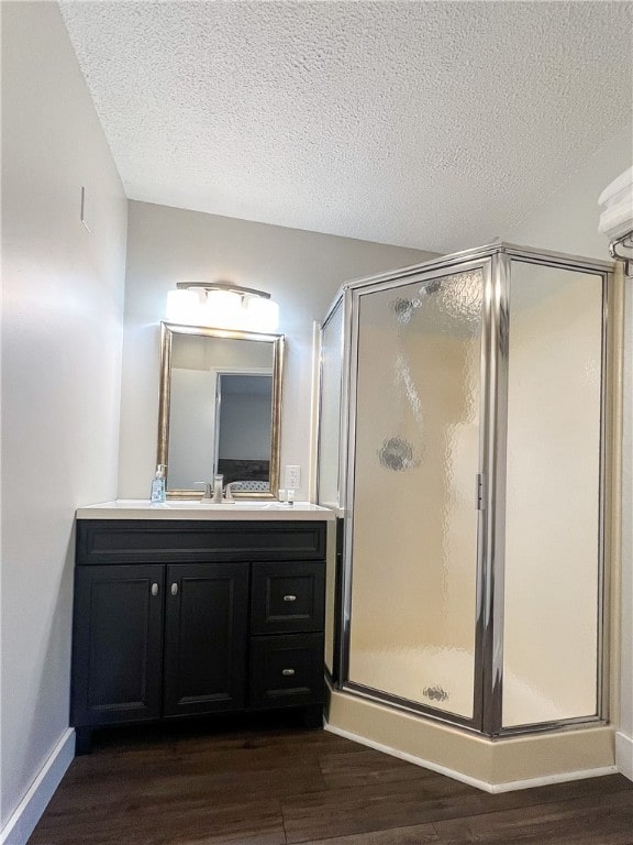 bathroom with vanity, wood-type flooring, an enclosed shower, and a textured ceiling