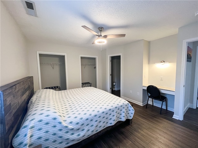 bedroom with built in desk, a textured ceiling, dark wood-type flooring, and ceiling fan