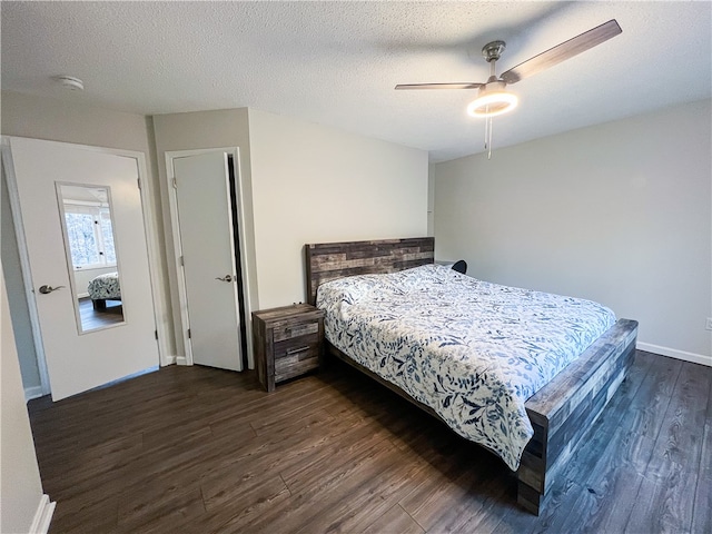 bedroom with a textured ceiling, dark wood-type flooring, and ceiling fan