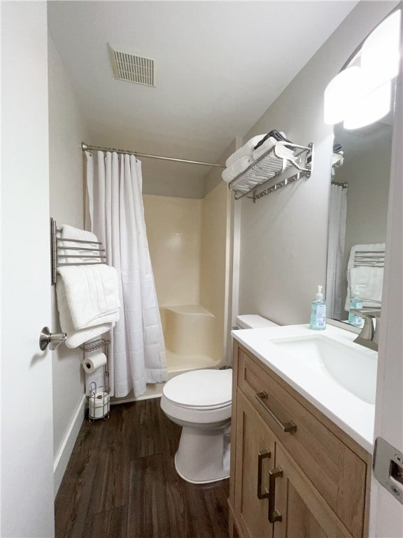 full bathroom featuring hardwood / wood-style floors, vanity, shower / tub combo, and toilet