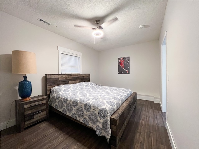 bedroom with ceiling fan, a textured ceiling, and dark hardwood / wood-style floors