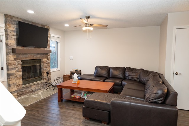 living room featuring a textured ceiling, a fireplace, dark hardwood / wood-style floors, and ceiling fan