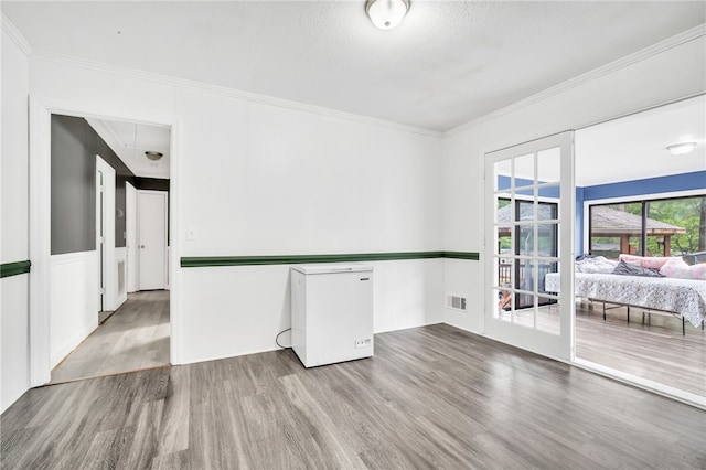 spare room with hardwood / wood-style flooring, crown molding, and a textured ceiling