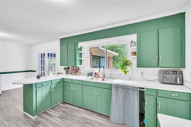 kitchen featuring a textured ceiling, green cabinets, sink, and light hardwood / wood-style flooring