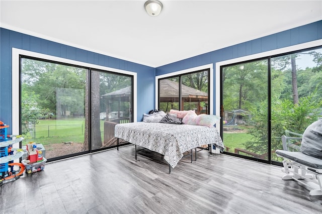 bedroom featuring multiple windows, ornamental molding, and hardwood / wood-style flooring