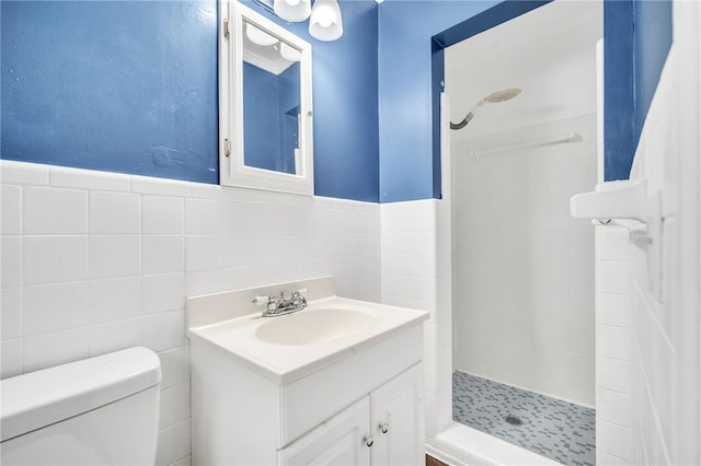 bathroom featuring tile walls, tiled shower, vanity, and toilet