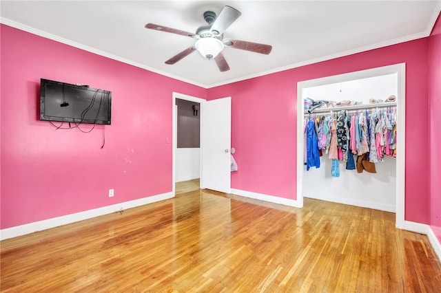 unfurnished bedroom with ornamental molding, a closet, ceiling fan, and hardwood / wood-style flooring