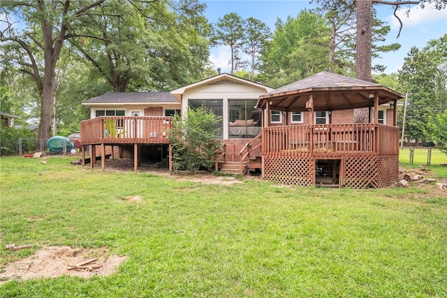 rear view of house featuring a deck, a lawn, and a sunroom