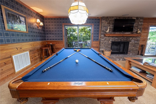 recreation room featuring carpet, a stone fireplace, wooden walls, and billiards