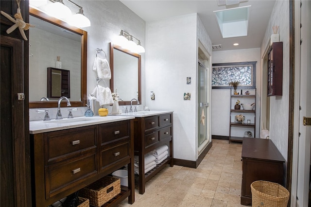 bathroom featuring a skylight, vanity, and a shower with door