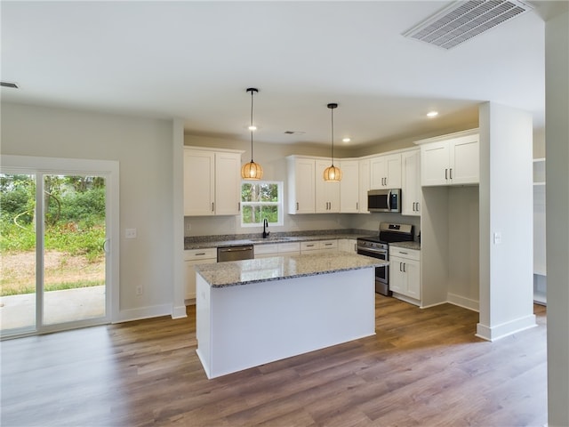 kitchen with a kitchen island, hardwood / wood-style floors, stainless steel appliances, and white cabinets