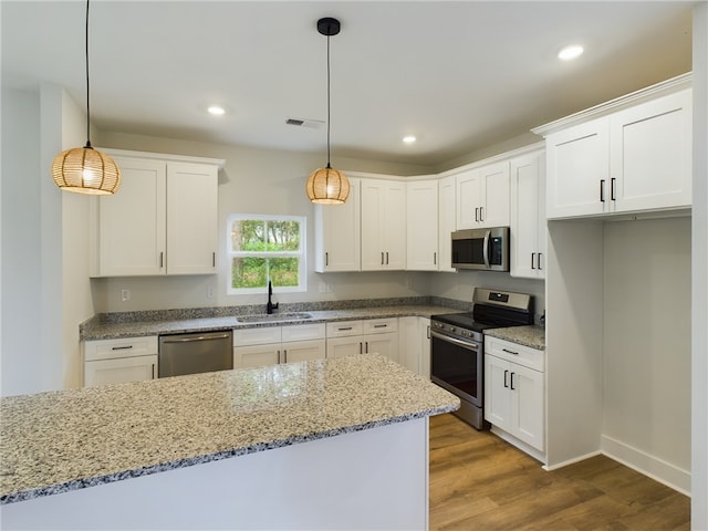 kitchen featuring stainless steel appliances, white cabinetry, and decorative light fixtures