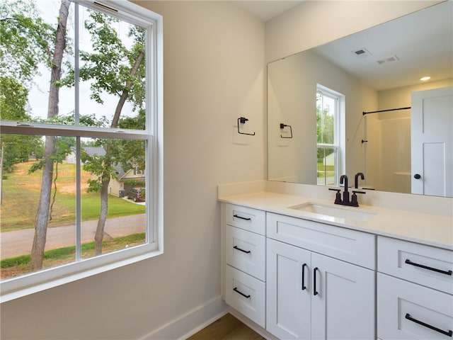 bathroom featuring a healthy amount of sunlight, hardwood / wood-style flooring, walk in shower, and vanity