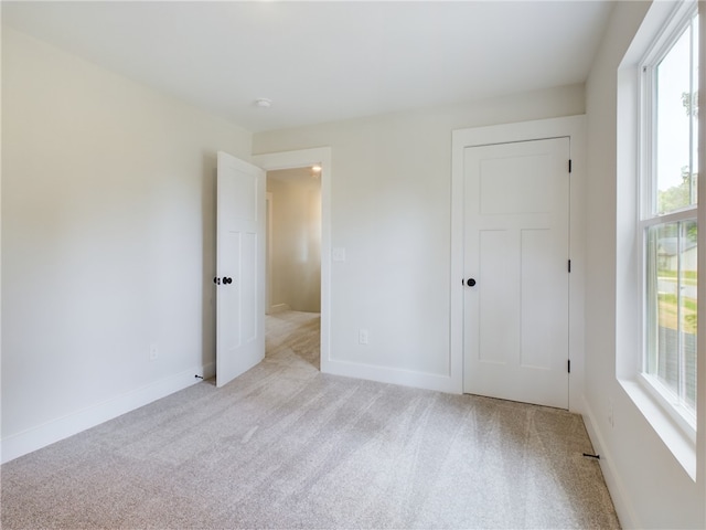 unfurnished bedroom featuring a closet and light colored carpet