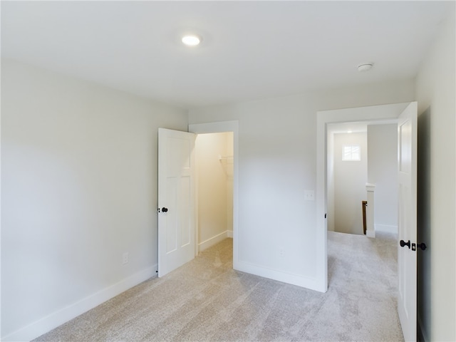 unfurnished bedroom with light colored carpet, a closet, and a walk in closet