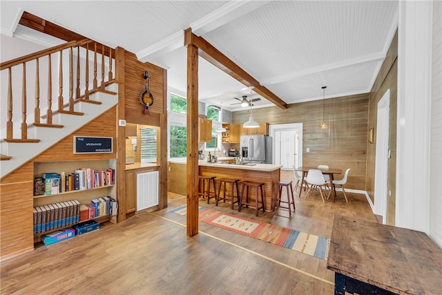 interior space with wood-type flooring, wooden walls, beam ceiling, and ceiling fan