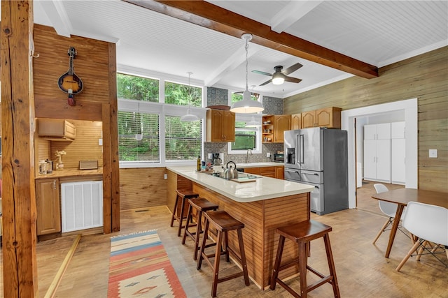 kitchen with high end fridge, wooden walls, kitchen peninsula, and light hardwood / wood-style flooring