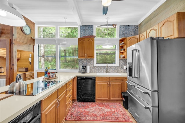 kitchen featuring backsplash, wood walls, black appliances, decorative light fixtures, and sink