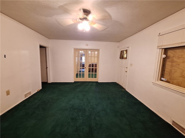 empty room featuring dark carpet, ceiling fan, french doors, and a textured ceiling