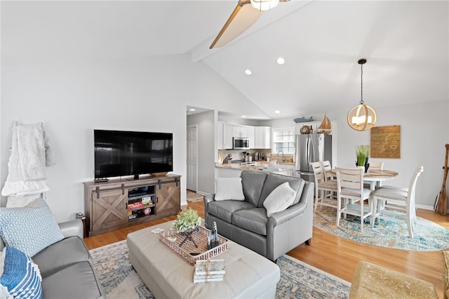 living room featuring high vaulted ceiling, light wood-type flooring, beamed ceiling, and an inviting chandelier