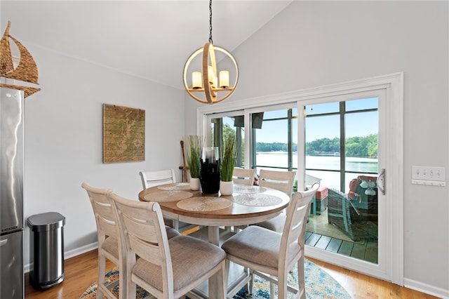 dining space featuring light hardwood / wood-style floors, lofted ceiling, a water view, and an inviting chandelier