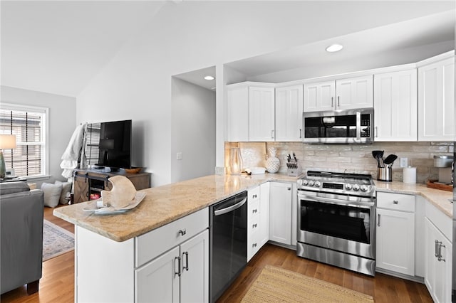 kitchen with kitchen peninsula, stainless steel appliances, backsplash, lofted ceiling, and white cabinets