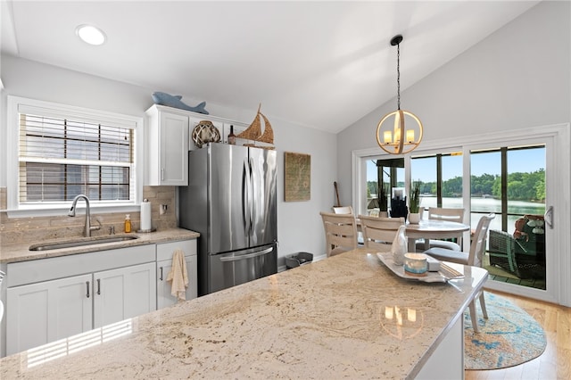 kitchen featuring tasteful backsplash, stainless steel fridge, sink, and white cabinetry