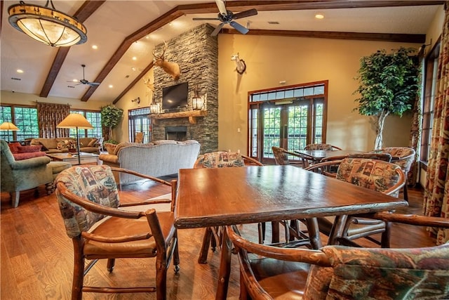 dining area featuring hardwood / wood-style floors, french doors, a fireplace, high vaulted ceiling, and beam ceiling