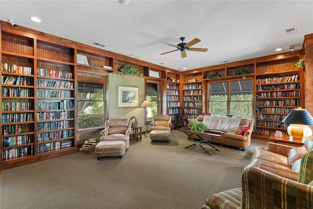 living area with ceiling fan, built in features, and carpet floors