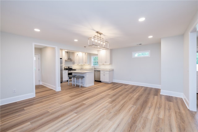 kitchen featuring wall chimney exhaust hood, a kitchen island, stainless steel appliances, and plenty of natural light