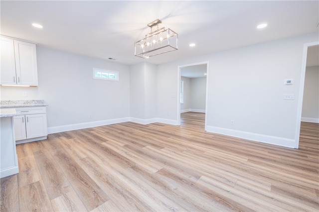 unfurnished dining area featuring light wood-type flooring and a chandelier