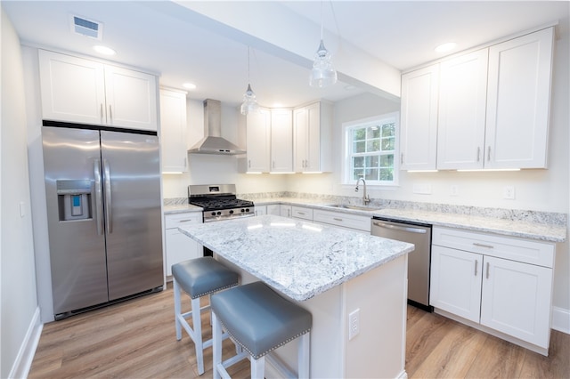 kitchen with wall chimney exhaust hood, white cabinetry, appliances with stainless steel finishes, and sink