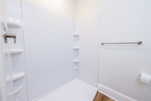 bathroom with a tile shower and hardwood / wood-style flooring