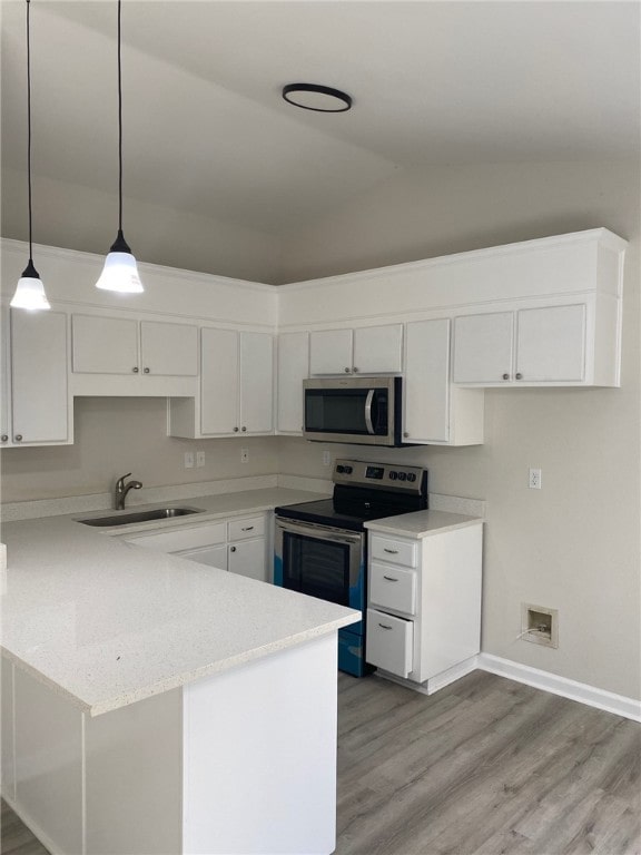 kitchen with stainless steel appliances, white cabinets, sink, light hardwood / wood-style flooring, and kitchen peninsula