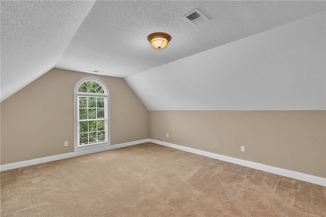 additional living space featuring lofted ceiling, a textured ceiling, and light colored carpet