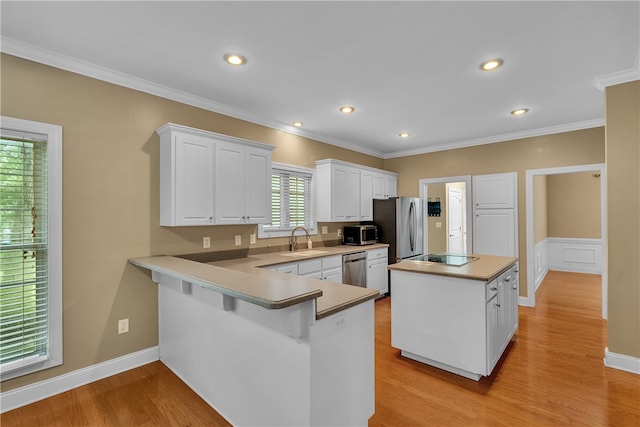 kitchen with white cabinets, kitchen peninsula, light hardwood / wood-style flooring, appliances with stainless steel finishes, and a center island