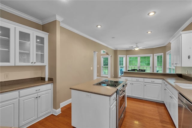 kitchen featuring white cabinets, stainless steel appliances, light wood-type flooring, and ornamental molding