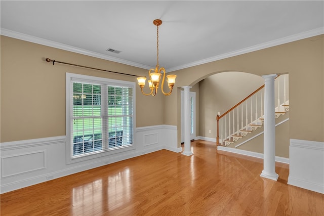 unfurnished dining area with light hardwood / wood-style flooring, decorative columns, ornamental molding, and a chandelier