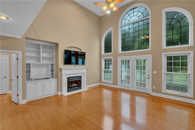 unfurnished living room featuring light wood-type flooring, ceiling fan, and high vaulted ceiling