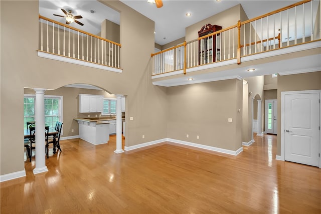 living room featuring light hardwood / wood-style floors, a high ceiling, ceiling fan, and ornate columns