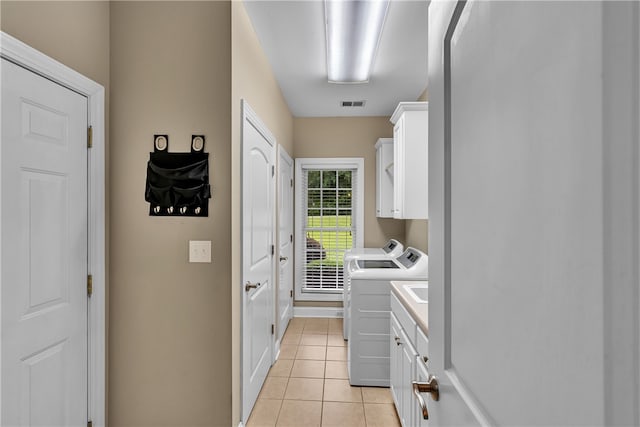 laundry room featuring light tile patterned floors, cabinets, and washer and dryer