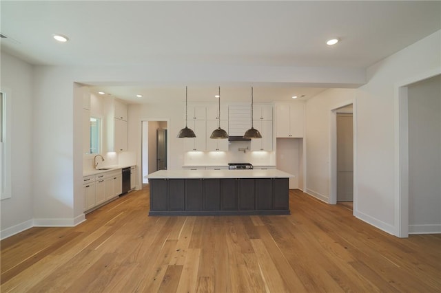 kitchen with pendant lighting, white cabinetry, dishwasher, a center island, and light hardwood / wood-style flooring