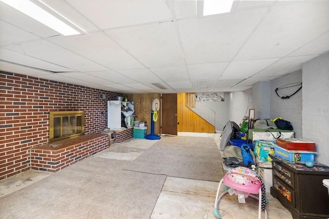 basement featuring a fireplace, a paneled ceiling, and wood walls