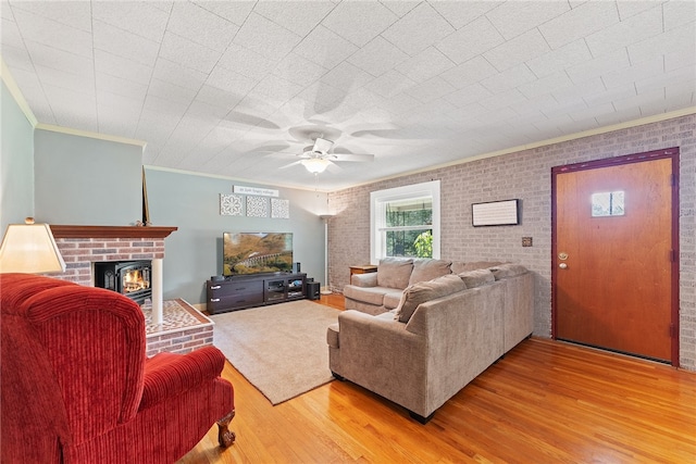 living room featuring wood-type flooring, brick wall, ornamental molding, and ceiling fan