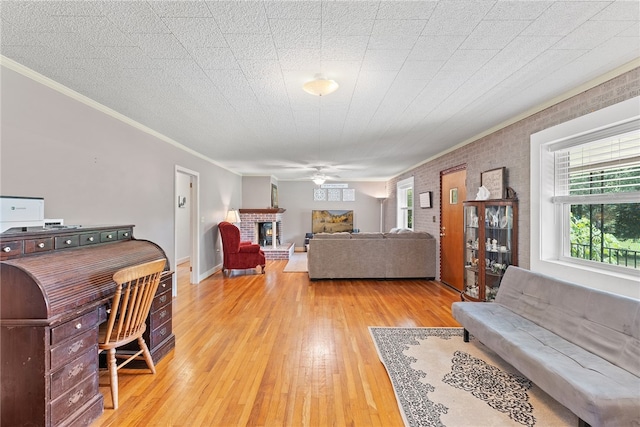 living room featuring a textured ceiling, a brick fireplace, hardwood / wood-style floors, crown molding, and ceiling fan