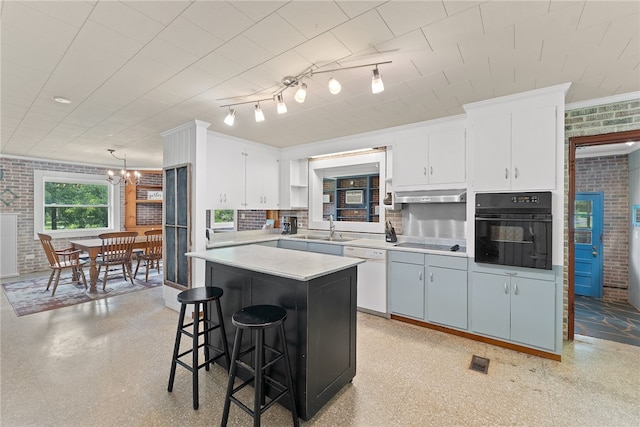 kitchen featuring white cabinets, black appliances, brick wall, and hanging light fixtures