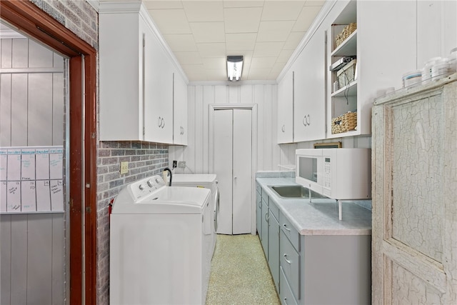 clothes washing area with separate washer and dryer and cabinets